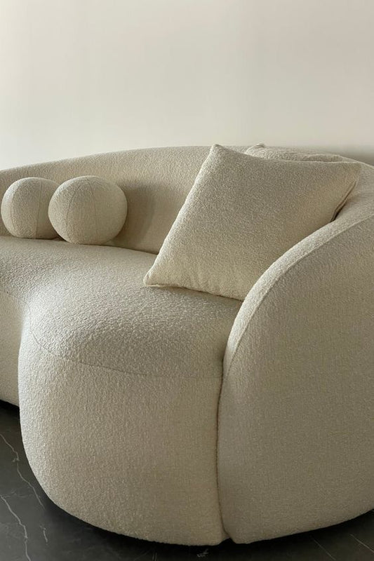 Beige sofa with spherical cushions on a neutral background